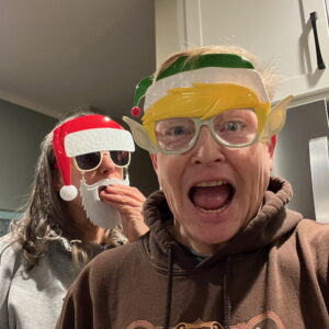 Kat and I with Christmas masks. Kat is eating a cookie. It's 2022